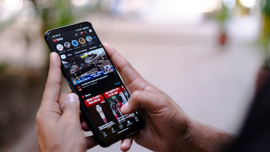 Close-up of hands using a smartphone to watch YouTube outdoors, showcasing digital connectivity.