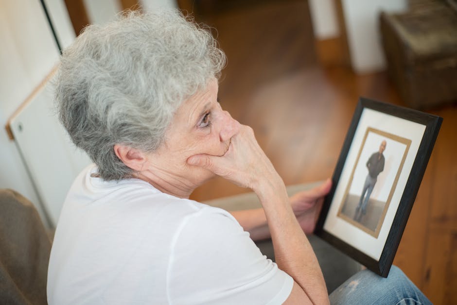 Thoughtful elderly woman with a framed photo, reflecting on memories.