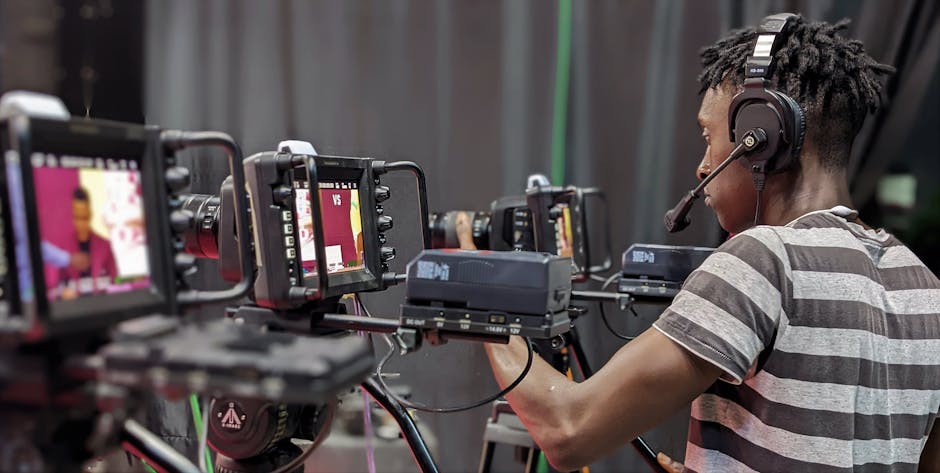 A videographer adjusts camera equipment during a live broadcast in a studio setting.