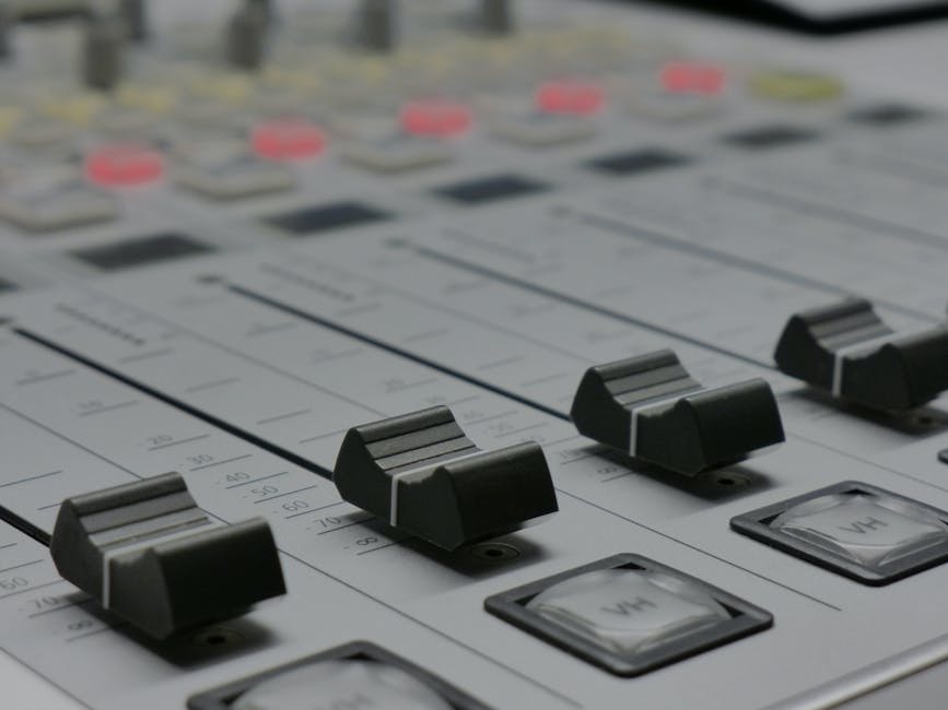 Detailed view of audio mixer sliders in a recording studio setting.